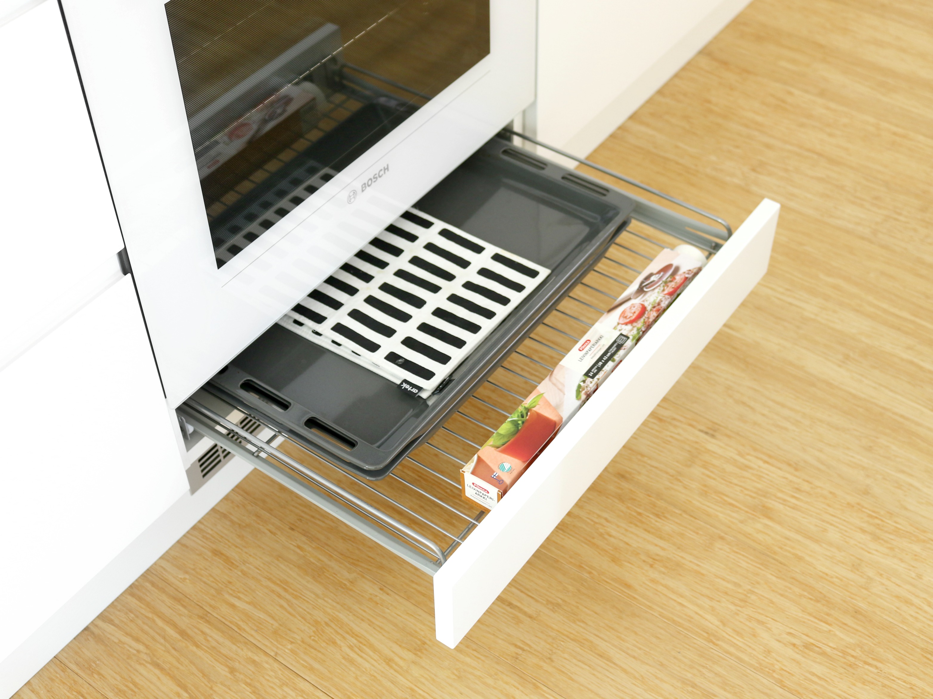 Minimalistinen valkoinen keittiö laatikoiden ja kaappien järjestely uunilaatikko peltien säilytys Omakotivalkoinen