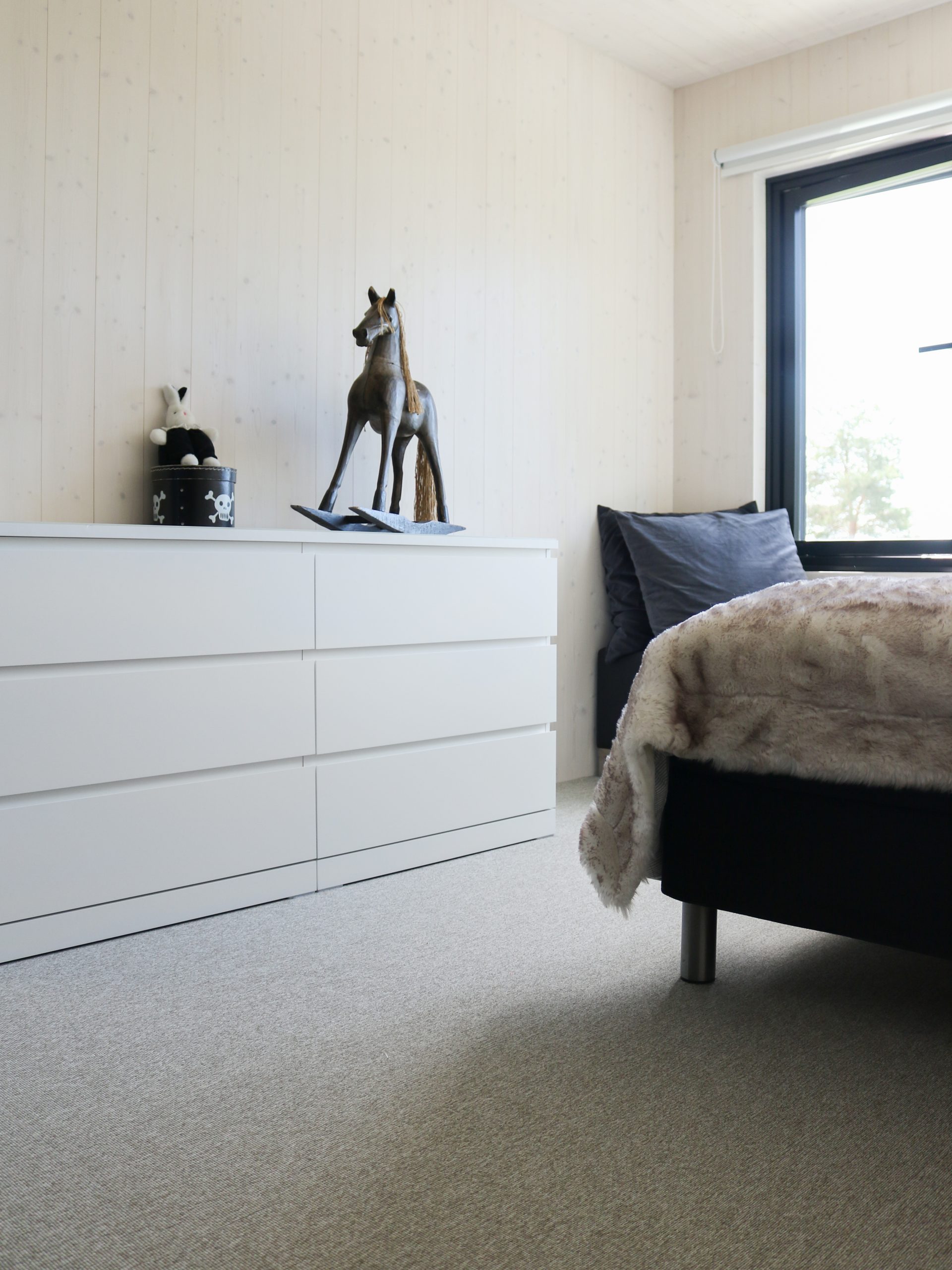 Makuuhuoneen minimalistinen sisustus saa pehmeyttä Forbo Tessera tekstiililaatan myötä. Sisustuskohde Omakotivalkoinen